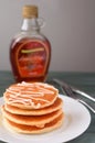 Stack of delicious pancakes with honey on plate on whit