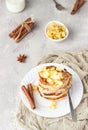 Stack of delicious sweet and spicy apple pancakes with fried caramelized apples and spices anise and cinnamon on a white plate