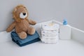 A stack of diapers, blue onesies, plush lion and baby supplies on changing table Royalty Free Stock Photo