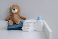 A stack of diapers, blue onesies, plush lion and baby supplies on changing table Royalty Free Stock Photo