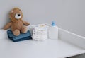 A stack of diapers, blue onesies, plush lion and baby supplies on changing table Royalty Free Stock Photo