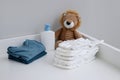 A stack of diapers, blue onesies, plush lion and baby supplies on changing table Royalty Free Stock Photo