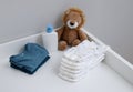 A stack of diapers, blue onesies, plush lion and baby supplies on changing table Royalty Free Stock Photo