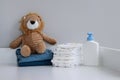 A stack of diapers, blue onesies, plush lion and baby supplies on changing table Royalty Free Stock Photo