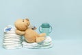 Stack of diapers with cute teddy bear toy pacifier bottle lying on table. set for infant newborn boy girl for baby shower present Royalty Free Stock Photo