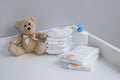 A stack of diapers, teddy bear and baby supplies on changing table Royalty Free Stock Photo