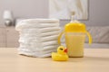Stack of diapers, toy duck and baby feeding bottle on wooden table indoors. Maternity leave concept Royalty Free Stock Photo