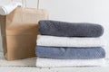 A stack of different bath towels near paper package on white wooden table. Spa and wellness, cotton terry textile Royalty Free Stock Photo