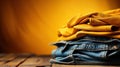 Stack of different blue and yellow jeans on the table. Yellow background. Fashion and retail concept. Copy space. Royalty Free Stock Photo