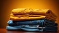Stack of different blue and yellow jeans on the table. Yellow background. Fashion and retail concept. Copy space. Royalty Free Stock Photo