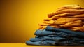 Stack of different blue and yellow jeans on the table. Yellow background. Fashion and retail concept. Copy space. Royalty Free Stock Photo