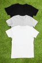 Stack of different coloured mens T-shirt on grass background