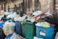 Stack of different types of large garbage dump, plastic bags, and trash bins near a wall in urban area in Environmental pollution