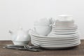 A stack of dishes. tableware on a brown wooden table. plates and cutlery, cups and kettle