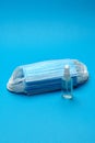 Stack of Disposable blue medical face masks and alcohol hand sanitizer antiseptic on blue background