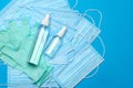 Stack of Disposable blue medical face masks, rubber latex gloves and alcohol hand sanitizer antiseptic on blue