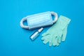 Stack of Disposable blue medical face masks, rubber latex gloves and alcohol hand sanitizer antiseptic on blue
