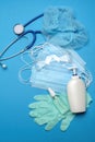 Stack of Disposable blue medical face masks, rubber latex gloves, goggles, stethoscope and alcohol hand sanitizer