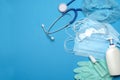 Stack of Disposable blue medical face masks, rubber latex gloves, goggles, stethoscope and alcohol hand sanitizer