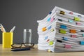 Stack of documents with binder clips and glasses on wooden table