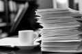 Stack of documents and coffee cup on desk in black and white office setting Royalty Free Stock Photo