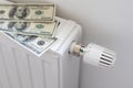 Stack of dollar banknotes on heating radiator battery with thermostat temperature regulator. Concept of expensive Royalty Free Stock Photo