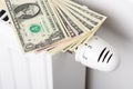 Stack of dollar banknotes on heating radiator battery with thermostat temperature regulator Royalty Free Stock Photo