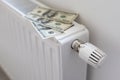 Stack of dollar banknotes on heating radiator battery with thermostat temperature regulator. Concept of expensive Royalty Free Stock Photo