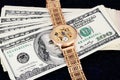 Stack of 100 dollar bills and gold watch on a dark background Royalty Free Stock Photo