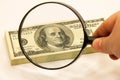 Stack of dollars under a magnifying glass. US dollar banknotes are enlarged with a large lens. A stack of American one hundred Royalty Free Stock Photo