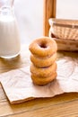 Stack donuts with a bottle of milk on wood background by the window