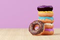 Stack of doughnuts with colorful icings and sprinkles on wooden surface. 3d render illustration.