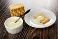 Stack of cookies, spoon in small bowl with condensed milk, cookie poured milk in saucer on wooden table