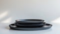 Stack of Elegant Black Plates on a Minimalist White Surface with Soft Lighting. Royalty Free Stock Photo