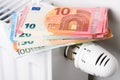 Stack of euro money banknotes on heating radiator battery with thermostat temperature regulator Royalty Free Stock Photo