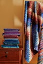 Stack of fabriÃÂs and quilt made in the bargello style on yellow wall background