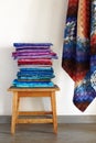 Stack of fabrics on a stool and quilt top made in the bargello style on neutral wall background