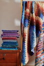 Stack of fabrics and quilt made in the bargello style on white wall background