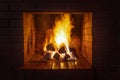 A stack of firewood burns with a bright hot flame in a red brick fireplace on a late dark cold evening Royalty Free Stock Photo