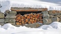 A Stack of Firewood Logs in a Stone Wall Covered in Snow Royalty Free Stock Photo