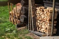 Stack of firewood next to old wooden cottage wall, sun lit grass