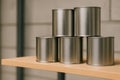 Stack of five blank metal cans arranged in a pyramid on a wooden shelf. Royalty Free Stock Photo