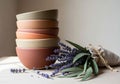 A stack of five ceramic bowls in various earth tones is placed on a light wooden surface. Next to Royalty Free Stock Photo