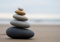 A stack of five smooth stones on a sandy beach. The pebbles vary in size and color, with the Royalty Free Stock Photo