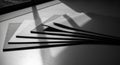 Stack of flat, dark rectangular objects casting sharp shadows in black and white image Royalty Free Stock Photo