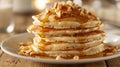 A stack of fluffy coconut pancakes drizzled with warm maple syrup and sprinkled with crunchy macadamia nuts