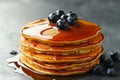 A stack of fluffy pancakes glistens with warm maple syrup and fresh blueberries, illuminated by the soft morning light, creating a Royalty Free Stock Photo