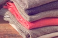 Stack of folded beige and pink clothes on brown wooden background. Female blouses pile