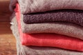 Stack of folded beige and pink clothes on brown wooden background.