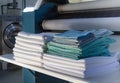 Stack of folded clean sheets or fabrics and industrial iron in an industrial laundry Royalty Free Stock Photo
